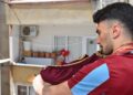 Evinin balkonundan tulum eşliğinde mahalleye moral veriyor