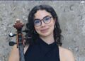 Olcay Varlı, Oxford Üniversitesi kabul belgesi ve çalgısıyla birlikte görülüyor.