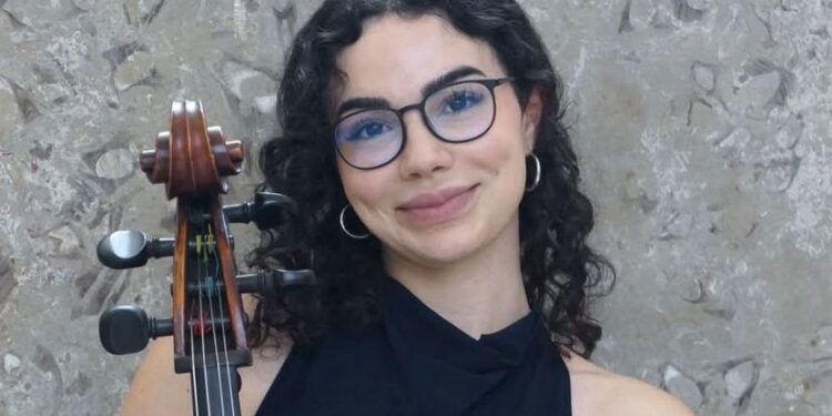 Olcay Varlı, Oxford Üniversitesi kabul belgesi ve çalgısıyla birlikte görülüyor.