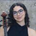 Olcay Varlı, Oxford Üniversitesi kabul belgesi ve çalgısıyla birlikte görülüyor.